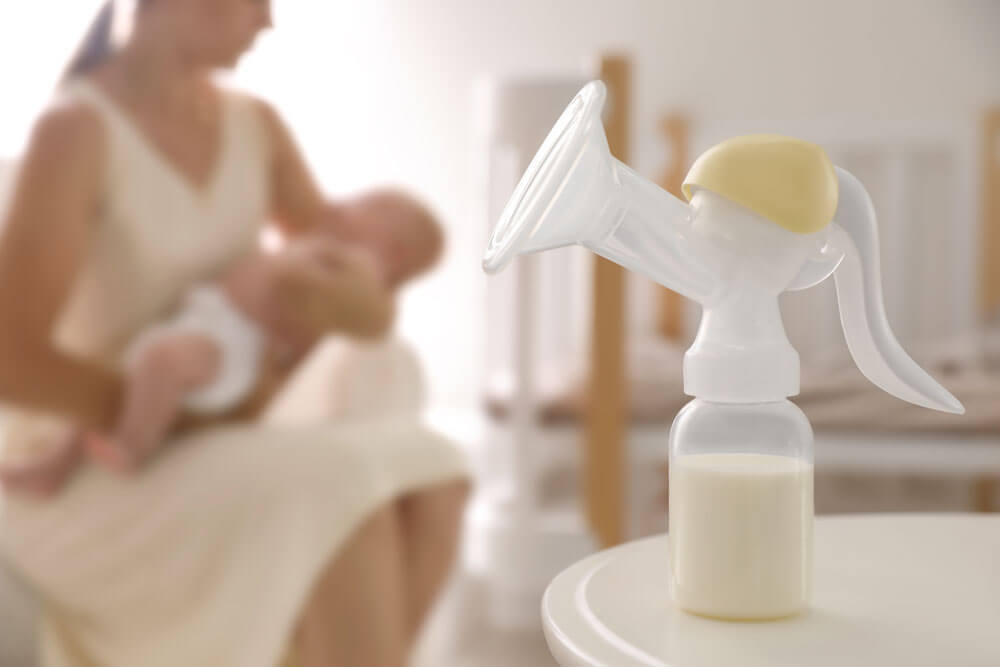 Mutter und kleines Baby drinnen, Fokus auf Tisch mit Milchpumpe