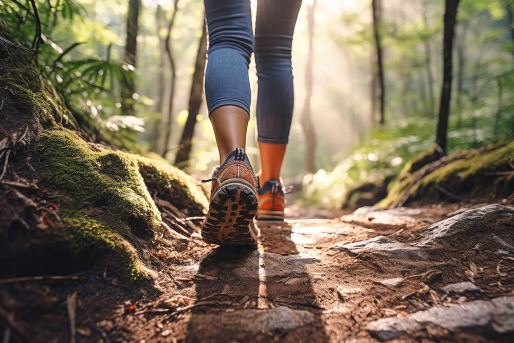 Rückansicht einer jungen Frau, die auf einem Waldweg spaziert, Nahaufnahme eines Schuhs